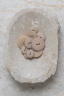 Les boutons vus de dessus, empilés au centre d'une pierre beige marbrée.