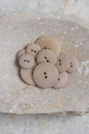Autre vue rapprochée des boutons sur la pierre beige marbrée, sous un angle différent.