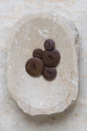 The buttons viewed from above, stacked at the center of a marbled beige stone.