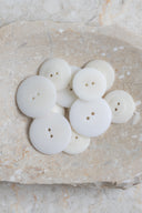 Les boutons vus de dessus, empilés au centre d'une pierre beige marbrée.