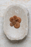 Top-down view of the buttons, stacked at the centre of a marbled beige stone.