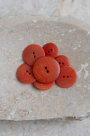 Top-down view of the buttons, stacked at the centre of a marbled beige stone.