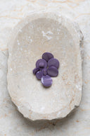 Domed round shank buttons with no visible holes, pearly mauve purple finish, piled in various sizes in an oval marbled beige stone dish.