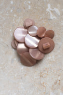 Les boutons vus de dessus, empilés au centre d'une pierre beige marbrée.