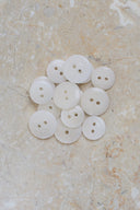 The buttons viewed from above, stacked at the center of a marbled beige stone.
