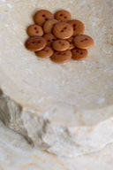 The buttons viewed from above, stacked at the center of a marbled beige stone.