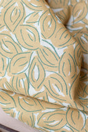 Close-up of the folds of the Petal fabric in mustard with a sage-green graphic leaf pattern.