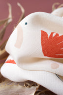 Close-up of the Sandstorm fabric in off-white, showing the abstract orange shapes and a small navy dot, near dried twigs.