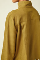 Patron Chemise Amirale – Vue dos, chemise kaki ample, empiècement dos et plis de dos visibles, fond beige – Atelier Brunette