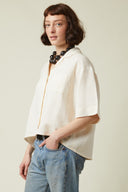 Patron Chemisette – vue de profil gauche, chemisette crème col chemisier, collier perles, jean – Atelier Brunette