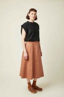 Patron La Jupe – Femme de face, jupe midi ample terracotta taille haute, top noir, fond beige – Atelier Brunette