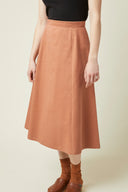 Patron La Jupe – Femme de face, jupe midi terracotta taille haute évasée, top noir, fond beige – Atelier Brunette