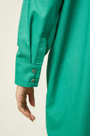 Patron Robe Chemise – Détail bas robe verte émeraude, boutons dorés au poignet, poche plaquée, fond beige – Atelier Brunette
