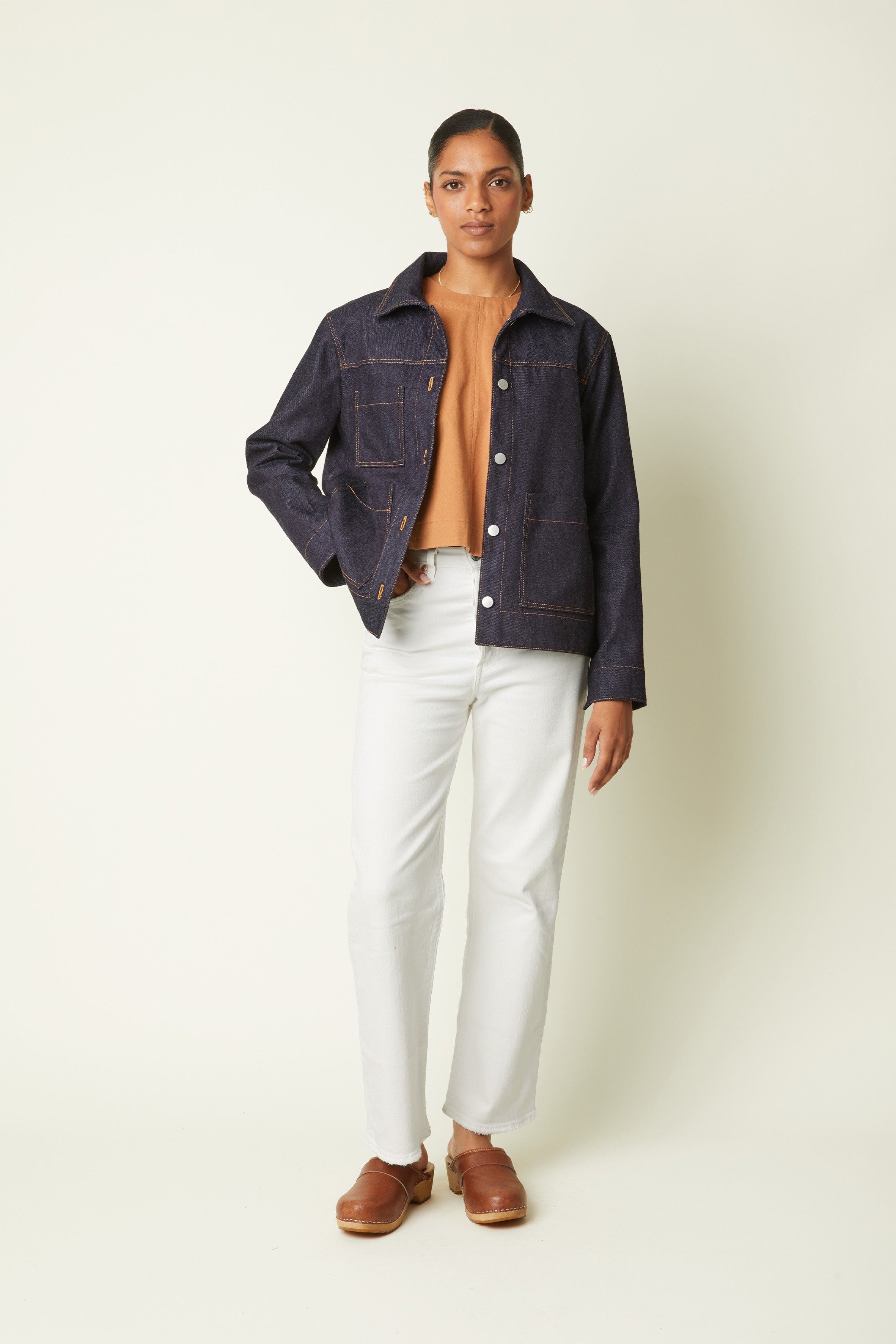 Patron Veste – vue de face, veste denim indigo coutures oranges, top caramel, jean blanc, sabots – Atelier Brunette