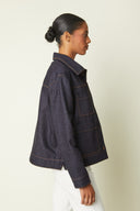 Jacket pattern – left profile view, jacket indigo denim orange stitching, white jeans – Atelier Brunette