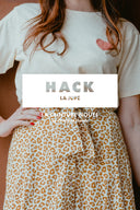 Skirt Hack – Woman, torso shot, skirt leopard print camel high waist tied belt, off-white t-shirt, brown background – Atelier Brunette