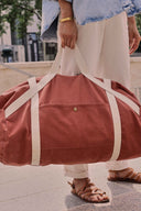Escapade Pack pattern – Woman holding the travel bag terracotta, handles off-white, casual outfit – Atelier Brunette