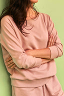 Sweatshirt pattern – bust shot, sweatshirt powder pink arms crossed, 3/4 ribbed sleeves, sage green background – Atelier Brunette