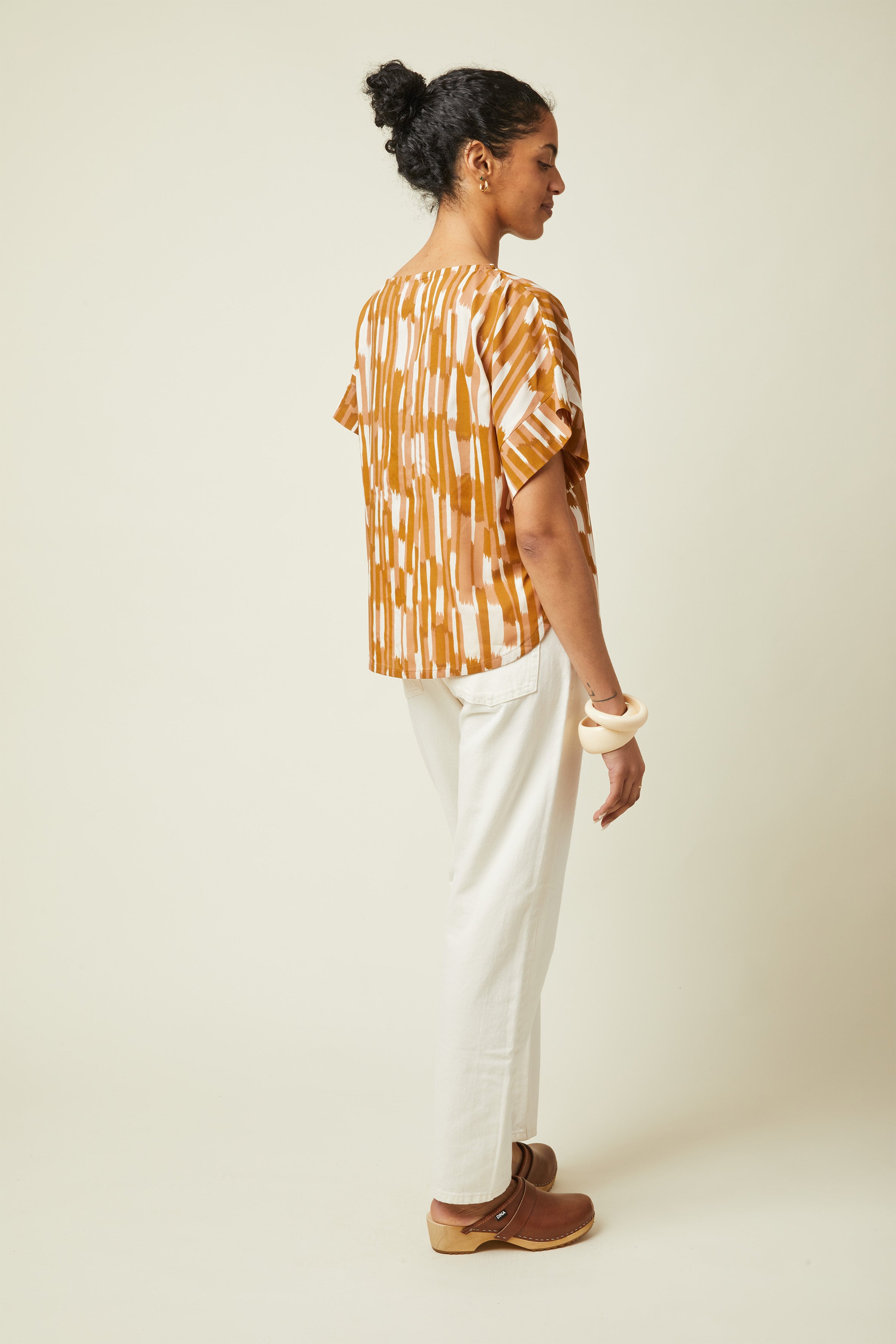 Patron Le Top Oversize – Femme de dos/côté, top imprimé géométrique ocre/terracotta, pantalon blanc – Atelier Brunette