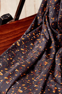 Gros plan sur les plis du tissu Candy Rock anthracite laissant apparaître le détail des confettis caramel, rouille et blanc cassé.