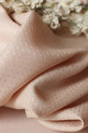 Crinkled dobby-weave fabric in blush pink, next to dried white yarrow flowers, close-up of the texture.