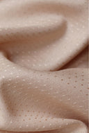 Macro close-up of a pale blush-pink viscose Swiss-dot fabric, folded in soft waves, showing the woven dot texture.