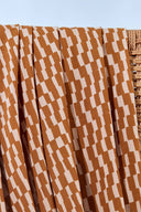 Tissu Domino moutarde plié, avec une coupelle en laiton contenant des boutons moutarde et écru assortis.