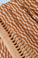 Tissu Domino moutarde et écru à motif graphique en escalier, en plis drapés contre un dossier en cannage tressé.