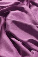 Tissu Flake rose orchidée suspendu à une tringle noire, en plis amples et aériens sur un fond rose.