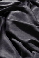 Tissu Flake anthracite suspendu à une tringle noire, en plis amples et aériens sur un fond clair.