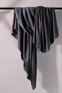 Tissu Flake anthracite plié, lisière effilochée visible, avec des boutons anthracite et caramel dispersés autour.