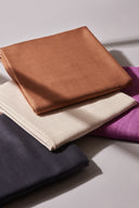Quatre coupons de double gaze Flake pliés côte à côte dans plusieurs coloris (caramel, écru, anthracite, fuchsia), montrant la gamme de couleurs.