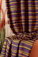Vue rapprochée du tissu Flow superposé en plusieurs plis, montrant la répétition du motif rayé moutarde, marine et fuchsia.