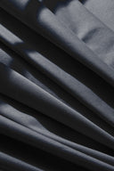 Gros plan en éventail sur les plis diagonaux du tissu gabardine légère bleu ardoise.