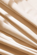 Gros plan en éventail sur les plis diagonaux du tissu gabardine légère écru.
