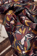 Gros plan sur l'imprimé floral graphique du tissu Hilma bordeaux, moutarde et sauge.