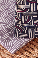 Tissus Hopscotch pliés dans deux coloris, mauve grisé et marine, posés sur un support en raphia tressé.