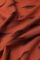 Tissu L'Ikat terracotta à motif de traits aubergine façon ikat, drapé en plis diagonaux.