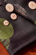 Gros plan sur les plis du tissu Jane noir laissant apparaître le détail des demi-cercles kaki et rose poudré.
