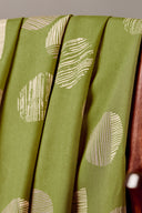Tissu viscose Jane vert matcha à motif graphique de demi-cercles écru, drapé sur l'accoudoir en bois d'une chaise vintage.