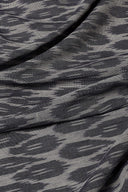 Tissu L'Ikat anthracite et gris clair à motif abstrait façon ikat, drapé en plis diagonaux sur voile fine.