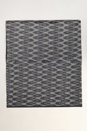 Tissu L'Ikat anthracite plié à plat, motif ondulant façon ikat visible sur l'ensemble de la pièce.