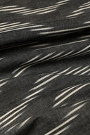 Tissu L'Ikat anthracite à fines rayures diagonales écru façon ikat, drapé en plis serrés.