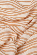 La Rayure 003 ecru fabric with caramel vertical stripes, lightweight voile folded flat, with a frayed selvedge visible.