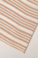 La Rayure 003 ecru fabric with caramel vertical stripes, rolled up showing the woven selvedge.
