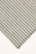 La Rayure 005 mottled ecru fabric with fine dotted charcoal horizontal stripes, rolled up showing the woven selvedge.