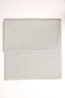 La Rayure 005 mottled ecru fabric with fine dotted charcoal horizontal stripes, folded in half and viewed from above.