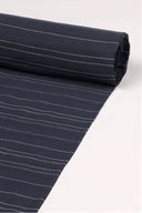 Close-up of the corner of the La Rayure 007 navy fabric with fine ecru horizontal stripes, highlighting the pattern and the frayed selvedge.