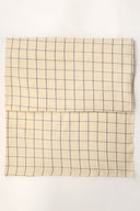 Tissu Le Carreau 002 jaune pâle à petits carreaux marine façon vichy, plié en deux et vu de dessus.