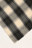 Le Carreau 005 ecru fabric with tartan-style charcoal checks, rolled up showing the woven selvedge.